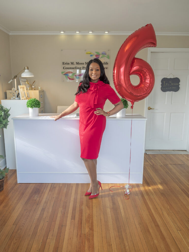 side profile portrait of Erin standing next to 6th anniversary balloon